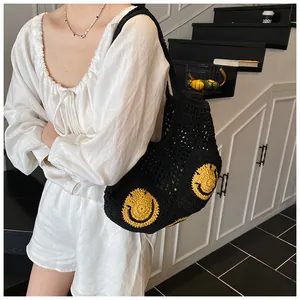 Detail of black crochet tote bag featuring vibrant yellow smiley faces on a woven texture