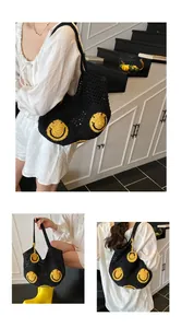 Detail of black crochet tote bag with yellow smiley face patch and hollow texture