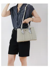 Dettaglio della borsa tote beige in pelle a grana litchi con elegante sciarpa di seta blu