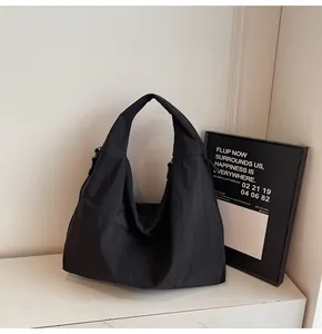 Close-up of black nylon tote bag with metal zipper and minimalist hobo style design