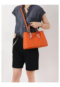 Dettaglio borsa tote in pelle arancione con foulard in seta sul manico e fibbia in metallo