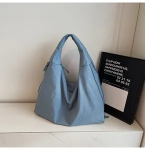 Detail of light blue wrinkled nylon fabric and wide shoulder strap on tote bag