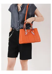 Dettaglio della borsa tote arancione in pelle martellata con foulard di seta sul manico