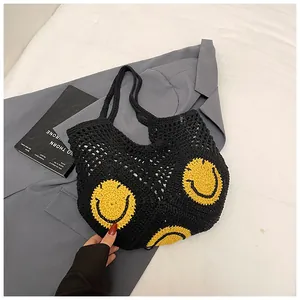 Detail of black crochet tote bag featuring embroidered yellow smiley faces and soft woven texture
