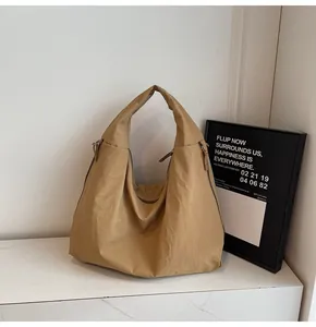 Detailed texture of khaki nylon tote bag with wide shoulder strap on marble surface