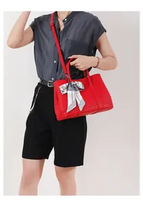 Dettagli della borsa tote in pelle martellata rossa con elegante foulard in seta sul manico