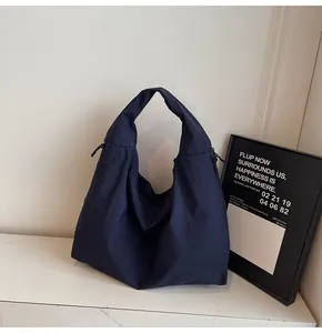Close-up of deep blue large capacity tote bag featuring textured nylon fabric and wide strap