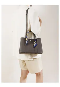 Dettaglio della borsa tote in pelle grigia con elegante foulard in seta sul manico