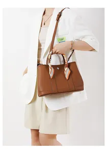 Dettaglio borsa tote in pelle martellata marrone con foulard di seta e chiusura a scatto