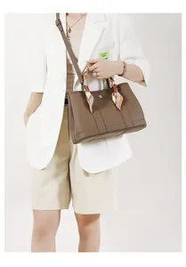 Dettaglio borsa tote in pelle marrone con foulard decorativo in seta arancione sul manico