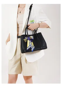 Dettaglio della borsa tote nera in pelle con motivo litchi e foulard in seta a righe