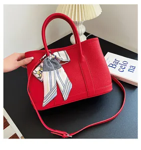 Dettaglio della borsa tote rossa in pelle martellata con foulard di seta sul manico