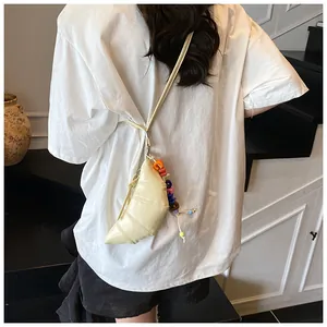 Detail der cremefarbenen Croissant-Tasche mit bunter Perlenkette am Schulterriemen