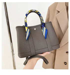 Dettaglio borsa a mano grigio scuro in pelle martellata con foulard di seta sul manico