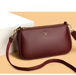 Detail of burgundy leather shoulder bag showing lychee grain texture and gold deer logo