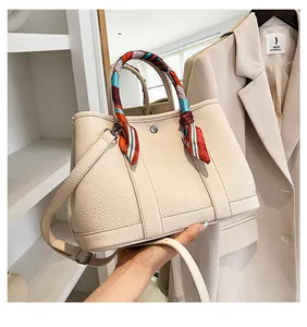 Dettaglio della borsa tote in pelle con sciarpa di seta elegante avvolta sui manici