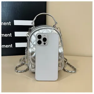 Détail d'un mini sac à dos argenté matelassé avec smartphone pour comparer la taille