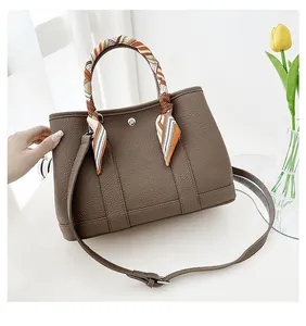Dettaglio borsa tote marrone scuro con grana litchi e foulard di seta sui manici