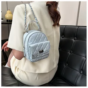 Détail du mini sac à dos matelassé bleu clair avec fermoir rotatif et bandoulière chaîne