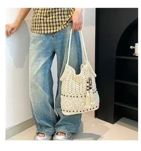 Detail of bohemian woven tote bag with crochet floral patterns and tassel charm