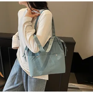 Light blue nylon tote bag with drawstring closure and silver rivets detail on pockets