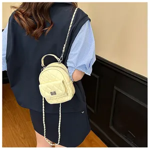 Mini sac à dos matelassé jaune pâle avec chaîne argentée porté par le mannequin