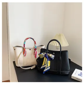 Dettaglio della pelle a grana di litchi e foulard di seta sulle borse a mano