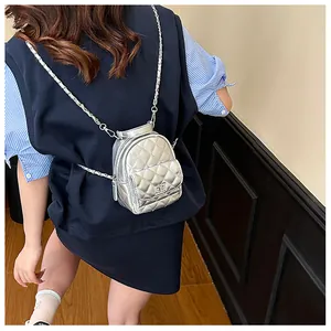 Détail d'un mini sac à dos argenté en similicuir matelassé avec chaîne et fermoir