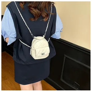 Vue détaillée du mini sac à dos blanc matelassé avec chaîne en métal et fermoir rotatif