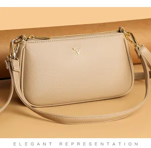 Close-up of beige leather crossbody bag with pebble texture and golden deer logo