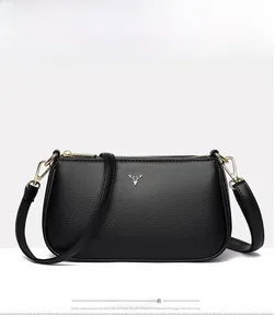 Front detail of black pebble leather crossbody bag with golden deer head logo accent