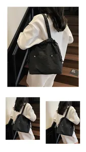 Close-up of black waterproof nylon tote bag with drawstring closure and silver rivet details