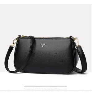 Detail of black pebbled leather crossbody bag with golden deer head logo and zipper