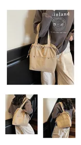 Detail view of beige nylon tote bag with drawstring closure and metal rivet accents