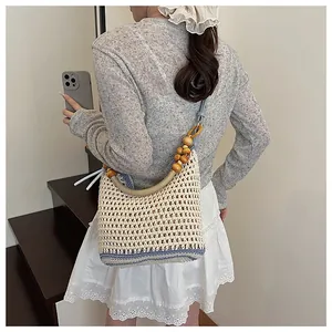 Detail of bohemian woven shoulder bag featuring decorative wooden beads and blue strap