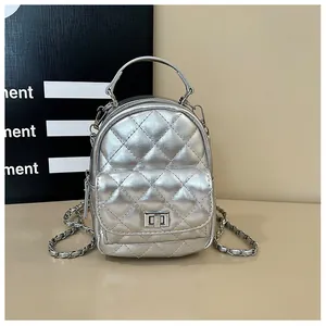 Détail d'un mini sac à dos argenté matelassé avec finition métallique et fermoir rotatif