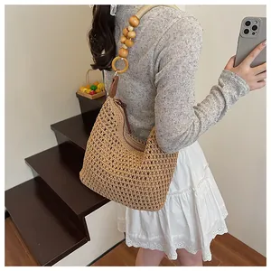 Detail of hand-woven straw tote bag featuring decorative wooden bead shoulder straps