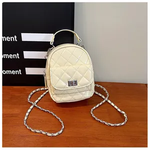 Détail du mini sac à dos matelassé crème avec chaîne métallique et poche à fermoir tournant