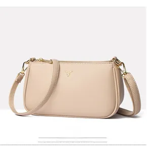 Close-up of beige lychee texture leather shoulder bag with golden deer head emblem detail