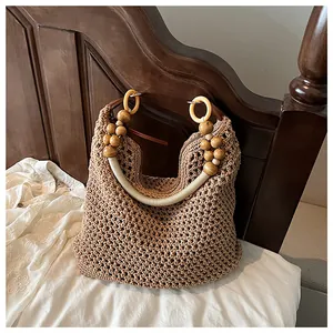 Detail of hand-woven beige shoulder bag featuring wooden beads and circular rings