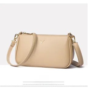 Side view showing lychee pattern leather and gold deer logo on beige crossbody bag