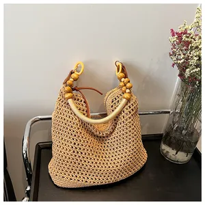 Detailed view of handwoven straw beach bag featuring wooden bead handles and a zipper