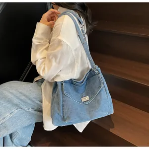 Détail d'un sac cabas en jean bleu avec fermoir métallique argenté et bandoulière