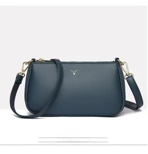 Detail of navy lychee texture leather handbag featuring a golden deer head logo accent