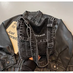 Détail du sac bandoulière en denim noir vintage avec broderie et boucles en métal