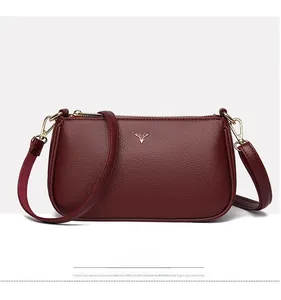 Front detail of wine red crossbody bag featuring gold stag logo and pebbled texture