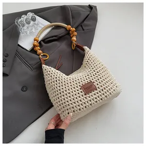 Detail of hand-woven beige tote featuring rustic wooden beads and a branded leather tag
