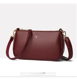 Macro shot of burgundy pebbled leather texture with a gold stag emblem on a women bag