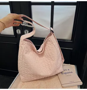 Détail du sac cabas matelassé rose clair montrant sa texture plissée et sa large bandoulière