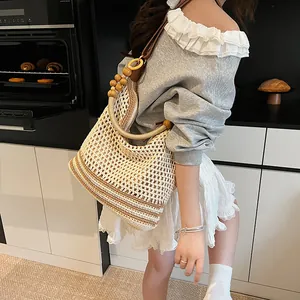 Handwoven straw shoulder bag with resin ring handles and wooden bead strap for beach travel